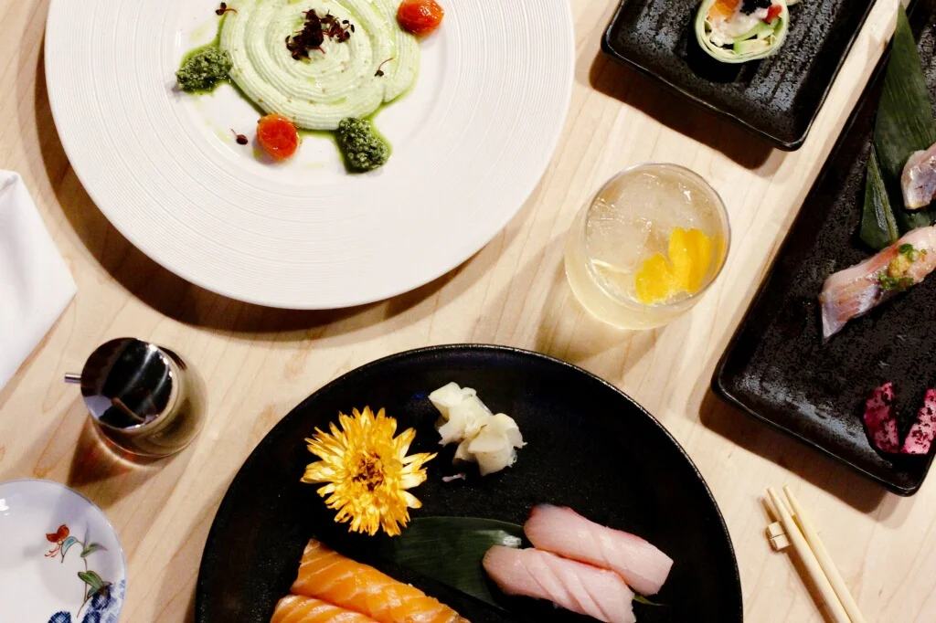 An overhead charcoal drawing of assorted small plates arranged on a wooden tray, warm cream and terracotta tones, inviting mood.
